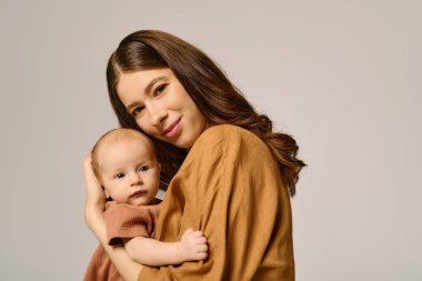 Güzel bir anne bebeğini kucağında tutar, sevgisini ve bakımını parlak bir ortamda gösterir..