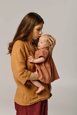 Genç bir anne sevgiyle gülümseyen çocuğunu kucağına alır ve neşe saçan içten bir bağ yaratır..