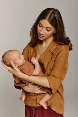 Güzel, genç bir anne o anda sevgi ve sıcaklık saçan çocuğunu nazikçe kucağına alır..
