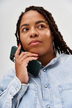 Saçları örgülü güzel bir Afrikalı Amerikalı kadın bir telefon görüşmesi sırasında düşünceli bir an yaşıyor..
