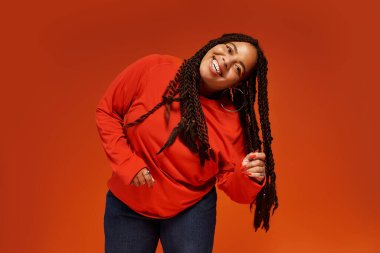 Neşeli bir Afrikalı Amerikalı kadın kendine güvenerek şık bir kıyafet içinde, parlak bir şekilde gülümsüyor..