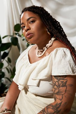 Yeşilliklerle çevrili, örgülü, yaz elbisesi içinde kendinden emin bir zenci kadın..