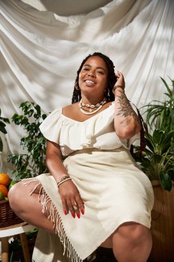 Örgülü parlak siyah bir kadın canlı bitkiler arasında zarifçe poz veriyor..