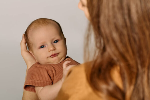 Sharing tender smiles, a beautiful young mother holds her baby, celebrating the joy of family life.