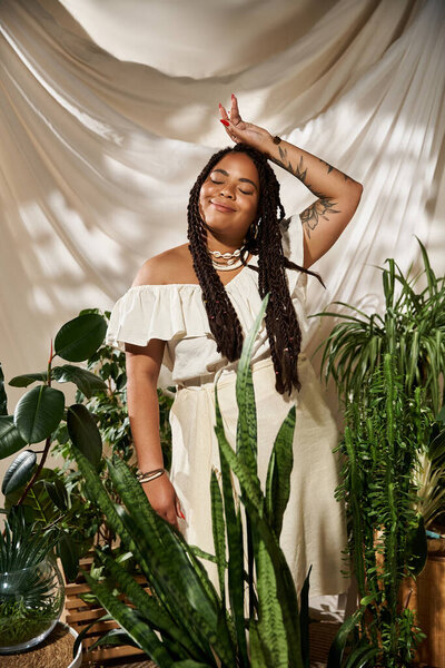 A joyful African American woman in a summer dress smiles amidst vibrant greenery, radiating bliss.