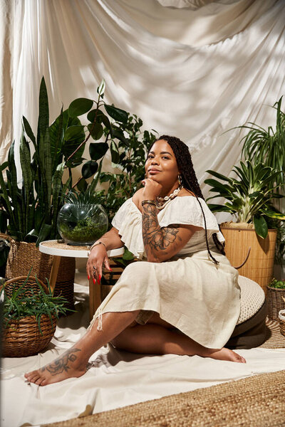 A pretty African American woman poses gracefully among vibrant green plants, radiating bliss.