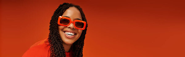 A beautiful African American woman with sunglasses poses playfully in a bright outfit, smiling joyfully, banner