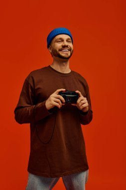 Yakışıklı genç adam elinde bir kamera tutarken ışıl ışıl gülümser, neşeli anıları çekmeye hazırdır..