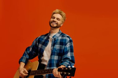 Parlak turuncu arka plan gitar çalan ve neşeyi paylaşan neşeli bir genci vurguluyor..