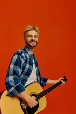 Gülümseyen genç adam gitar telleri çalıyor, tutku ve enerjiyle anın tadını çıkarıyor..