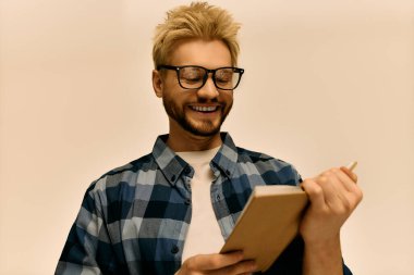 Yakışıklı genç adam defterine neşeli bir ifadeyle yazmaktan hoşlanıyor..