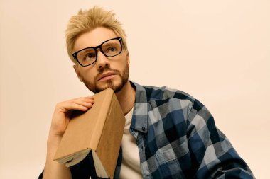 Düşünceli genç adam, sakin bir ortamda fikirleri düşünürken bir kitabı yakın tutuyor..