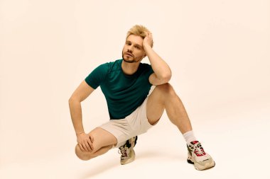 Deniz mavisi gömlekli ve şortlu genç bir adam stüdyoda poz verirken yaratıcılık gösteriyor..