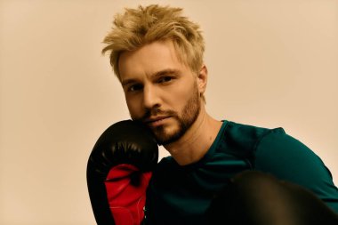 Genç adam cazibesini ve gücünü bir boks eldiveniyle poz verirken sergiliyor. Kendine güveni tam..