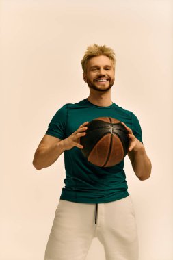 Yakışıklı genç adam elinde basketbol topuyla gülümsüyor, kendine güven ve neşe saçıyor..