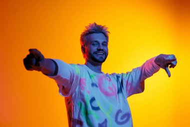 Neşeli genç adam, etrafını saran renkli ışıklarla, sanatsal enerji sergiliyor..