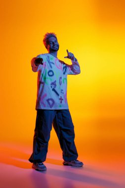 Yakışıklı genç adam, parlak ve sanatsal bir geçmişe karşı şakacı bir şekilde poz veriyor..