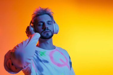 Yakışıklı genç adam kulaklıkla müzik dinliyor, parlak tonların altında neşeli bir anda kaybolmuş..