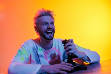 Neşeli genç bir adam coşkuyla video oyunları oynuyor, neşe ve heyecan dolu..