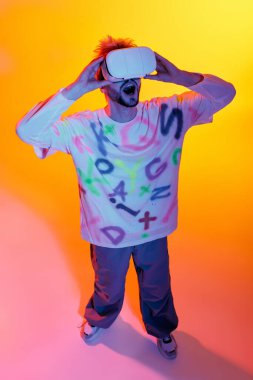 Enerjik genç adam, renkli bir ortamda büyüleyici teknolojiyle meşgul oluyor..