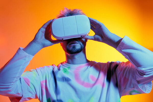 Handsome young man engages with a virtual reality headset amid an electric backdrop.