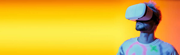 Confident young man engages with virtual reality while vibrant colors fill the background.