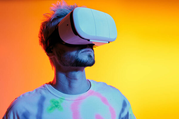 A young man enjoys virtual reality in a colorful, vibrant setting with playful lighting.