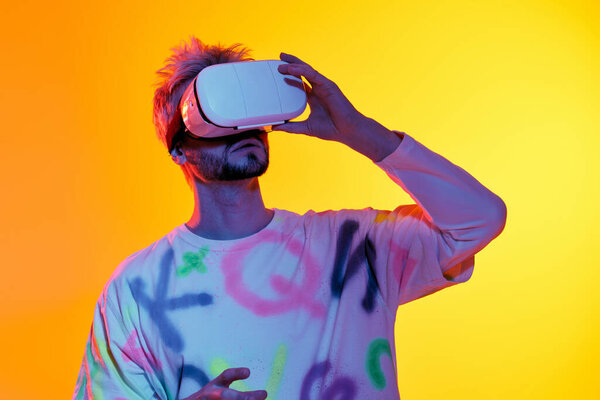 A young man in a VR headset explores a vibrant, creative virtual world.
