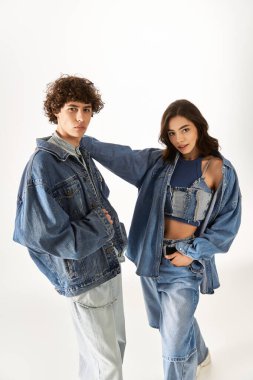Tarz sahibi genç çift, eşgüdümlü kot giysiler içinde, sevgi ve güven saçarak birlikte poz veriyorlar..