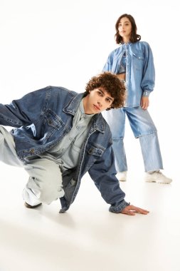 Genç bir çift, parlak bir alanda poz verirken şık kot kıyafetlerle sevgilerini ifade eder..