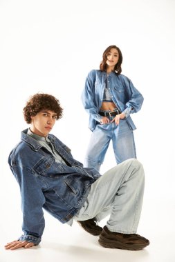 Şık bir çift, eşleşen kot kıyafetleriyle poz verir. Parlak bir alanda sevgi ve güven yayarlar..