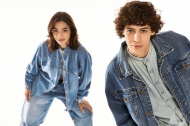 Şık bir çift, modaya olan sevgilerini, uyumlu kot elbiseleriyle, neşeli bir pozda sergiliyor..