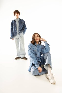 Genç çift, asgari arkaplan karşısında şık bir kotla aşkı gösteriyor.