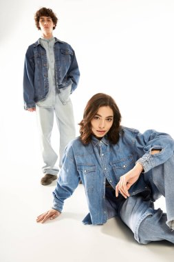 Yakışıklı bir adam ve güzel bir kadın parlak bir stüdyoda moda kot giysileri sergiliyor..