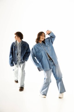 Şık genç çift, moda kıyafetlerini bir stüdyoda oyuncu pozlar vererek sergiliyor..