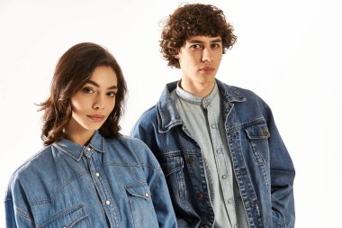 Genç bir çift parlak bir alanda şık kot elbiseleriyle hava atıyor..