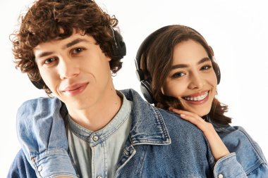 Neşeli genç bir çift bir anı paylaşıyor, müzik dinlerken kucaklaşıyorlar, ikisi de modaya uygun giyinmiş..