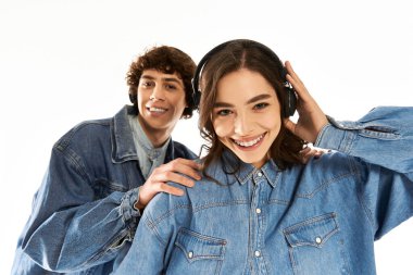 Neşeli çift, kulaklık ve şık kot giysiler giyerken sevgi dolu bir anı paylaşıyor..