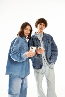 Şık genç çift, birlikte poz verirken akıllı telefonlarının keyfini çıkararak tasasız bir anı paylaşıyor..