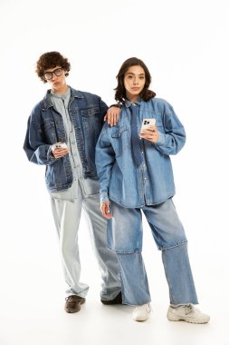 Genç çift, modaya uygun kot giysiler içinde güven içinde poz verirken aşk ve tarz sergiliyor.