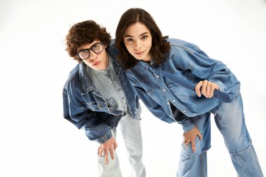 Genç bir çift, şık kot kıyafetlerini parlak bir stüdyoda modellerken eğleniyor..