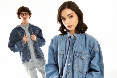 Genç çift aşk ve tarz saçıyor. Parlak bir arkaplan karşısında eşleşen kot kıyafetlerle poz veriyorlar..