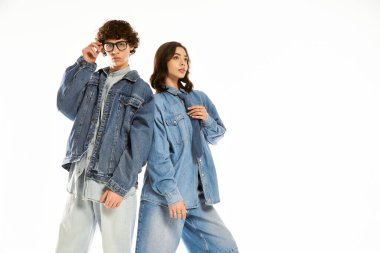 Genç çift, şık bir stüdyoda şık kot kıyafetlerini sergileyerek birlikte poz veriyor..
