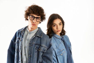 Genç bir çift birbirine yakın duruyor, modaya uygun kot kıyafetleri içinde aşk ve tarz yayıyorlar..