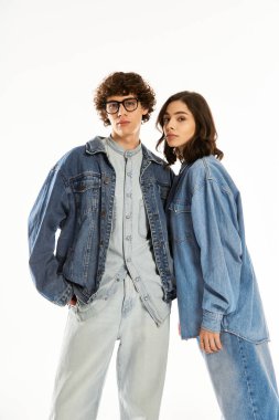 Genç çift, parlak bir arka planda eşleşen kot elbiselerle aşkı gösteriyor..