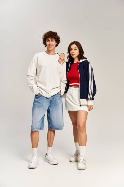 Şık genç bir çift birlikte gülümsüyor, profesyonel bir stüdyoda mutluluk saçıyor..