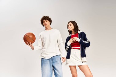 Genç çift, ellerinde basketbol topu ve kahkahalarla şık bir stüdyoda neşeli bir anı paylaşıyor..