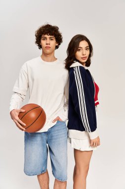 Sırt sırta genç bir çift, basketbol oynayan bir adam, modern moda sergiliyor..