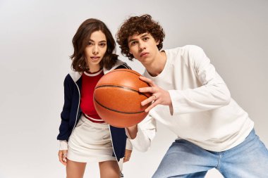 Genç ve şık bir çift, aşklarını sergilemek için basketbol topuyla eğleniyor..