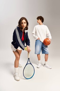 Genç çift, tenis ve basketbol oynarken atletizm ve moda becerilerini sergiliyor.